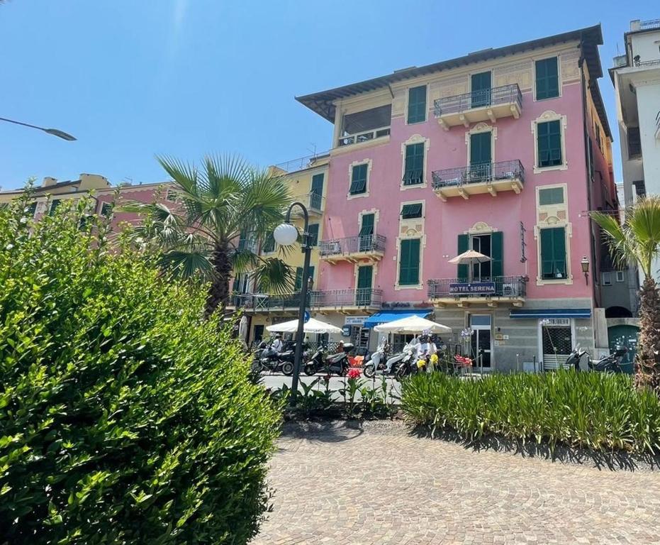 阿伦扎诺塞瑞纳酒店的粉红色的建筑,前面设有桌子和遮阳伞