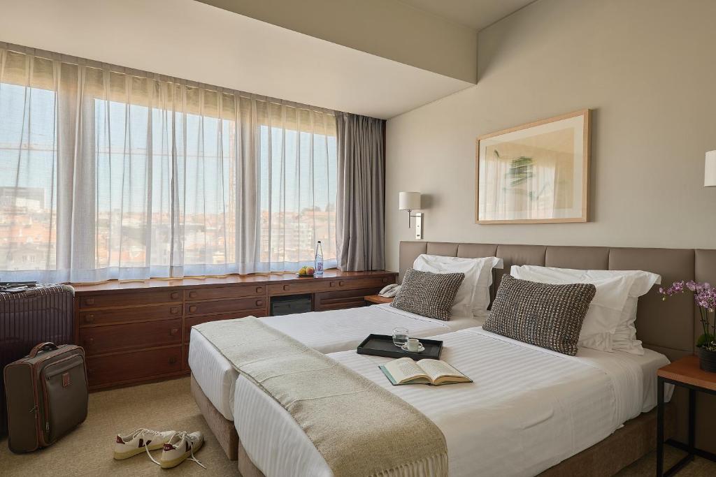 里斯本多卡洛斯公园酒店的酒店客房带大型白色床和窗户。