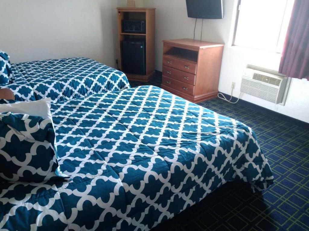 苏华德日落套房酒店的卧室配有蓝色和白色的床和梳妆台。