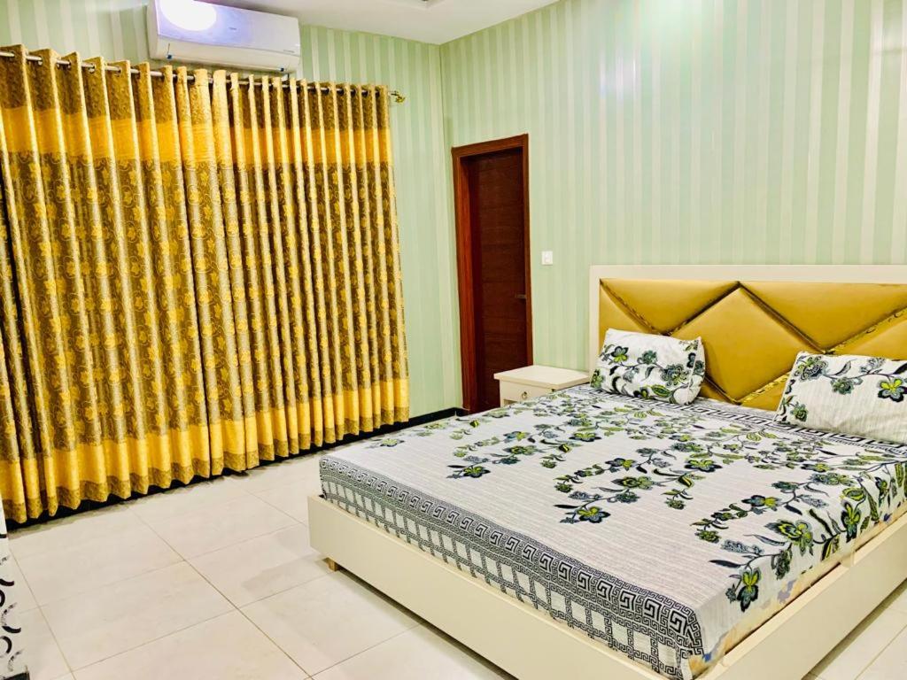 伊斯兰堡The Crown的一间卧室配有大床和黄色窗帘