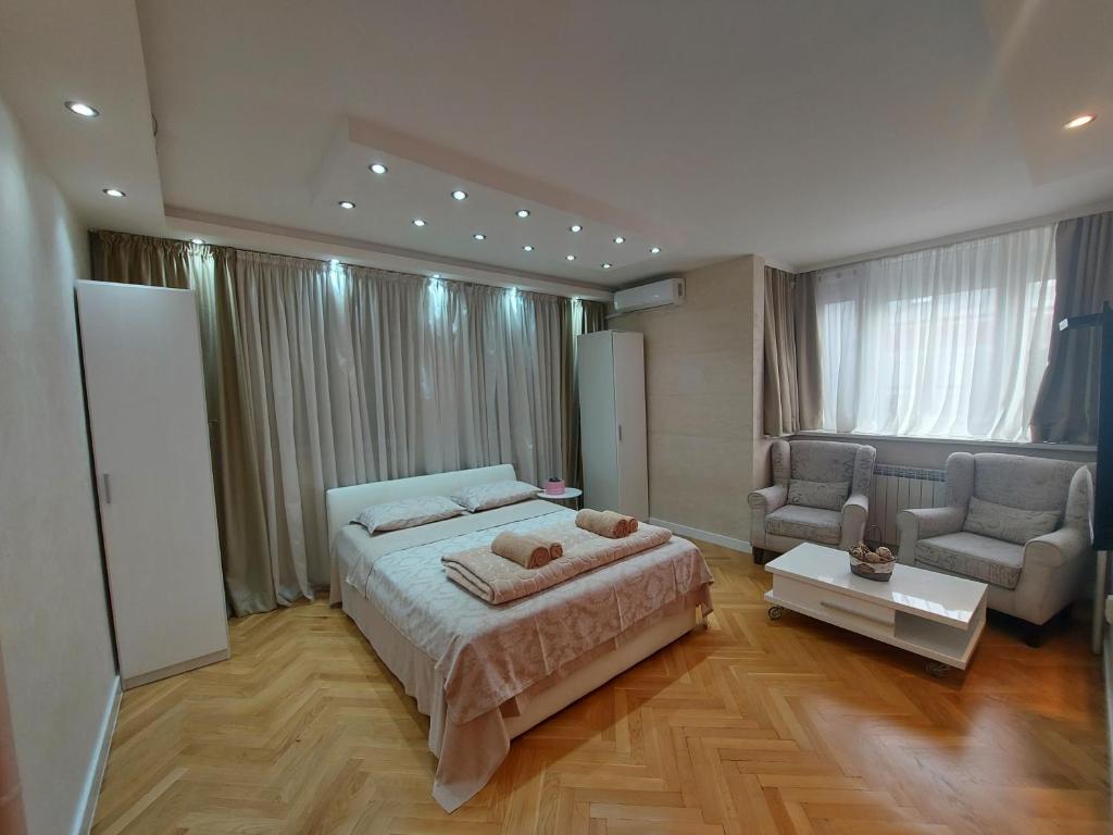 贝尔格莱德Arena Relax Apartman的一间卧室配有一张床、一张沙发和一把椅子
