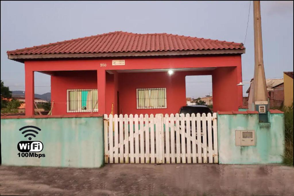 伊利亚孔普里达Casa Pestana - Ilha Comprida的前面有白色围栏的红色房子
