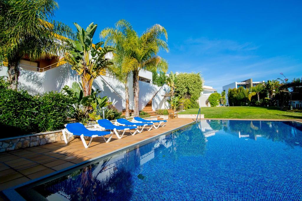 阿尔布费拉Pine Tree Apartments - Praia da Coelha - Albufeira的一个带蓝色椅子的游泳池