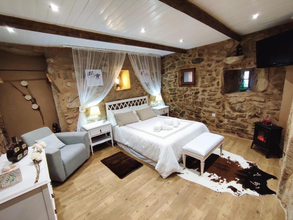 MazaricosA Cuadriña的一间卧室设有一张大床和石墙