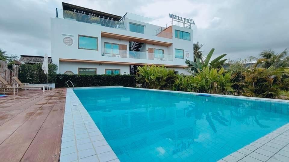 迈考海滩Wayla Villa@Maikhaobeach的一座别墅,在一座建筑前设有一个游泳池