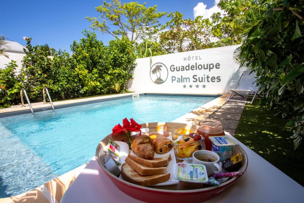 圣弗朗索瓦Hôtel Guadeloupe Palm Suites的池边桌子上的盘子