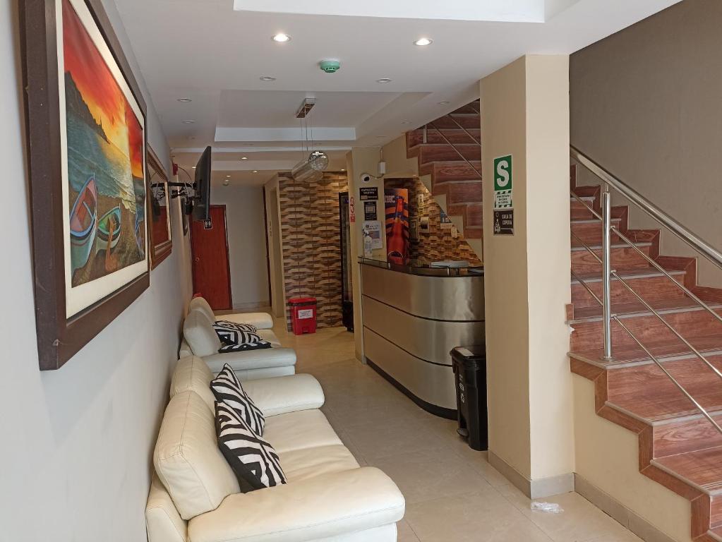 齐克拉约HOTEL ALFONSO UGARTE的一间设有两张白色沙发和楼梯的等候室
