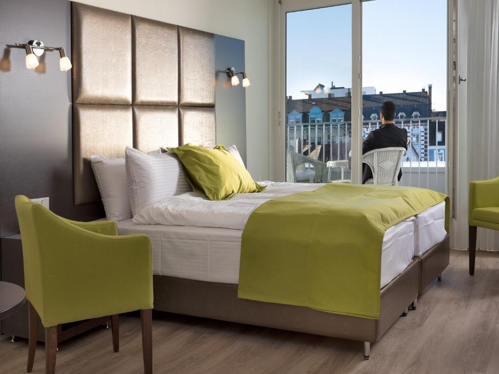 莱茵费尔登Boutique Hotel Bellevue Rheinfelden / Basel的一间卧室,卧室配有一张床,而人坐在椅子上