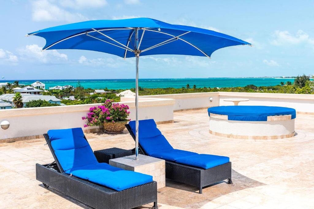 Turtle CoveSea Esta Studio III - Cozy for Couples!的天井上摆放着一双蓝色的椅子和一把遮阳伞