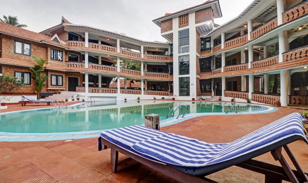 可瓦兰Treebo Trend God'S Own Country Ayurveda Resorts的一座大型建筑,在一座建筑前设有一个游泳池