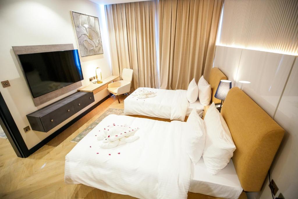 多哈A&H Hotel Apartment的酒店客房设有两张床和一台平面电视。