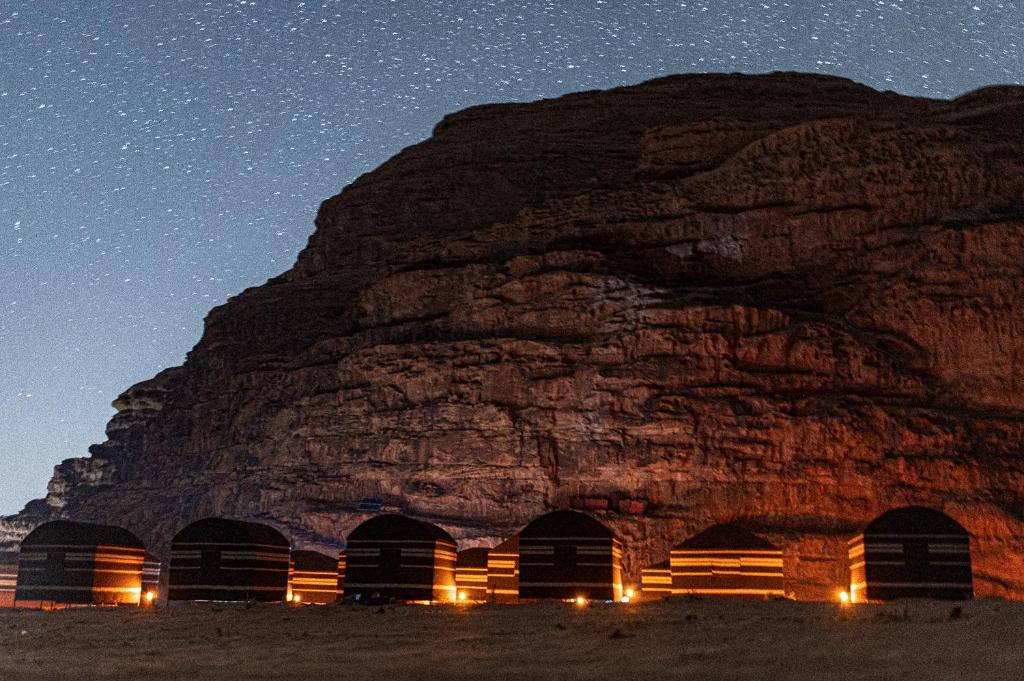 瓦迪拉姆Wadi Rum Magic Nature Camp的一群小屋在晚上在山前