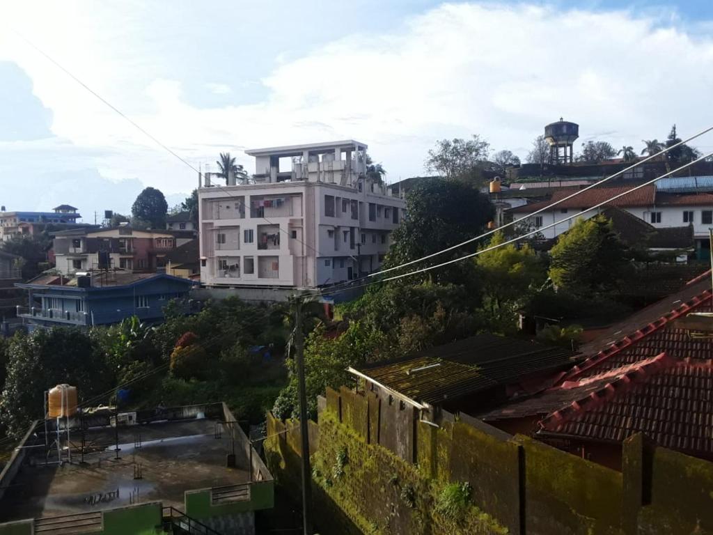 马迪凯里Kamadhenu Residency Homestay Apartment Coorg Madikeri的城市顶部的白色建筑