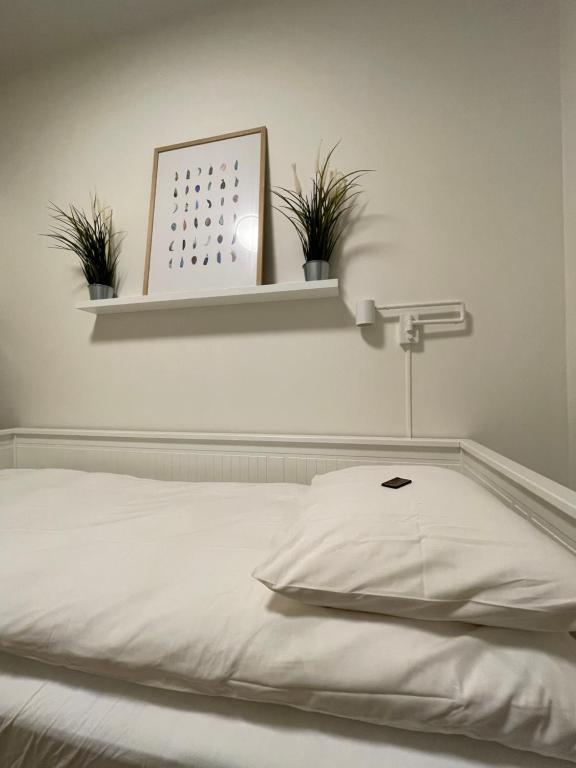 利勒斯特罗姆Newer apartment, with all you needs! 25 minutes to Oslo City or OSL Airport!的一张白色的床,上面有架子和植物