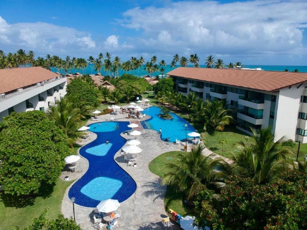 塔曼达雷Carneiros Beach Resort - Apto 214D的享有带游泳池和遮阳伞的度假村的空中景致