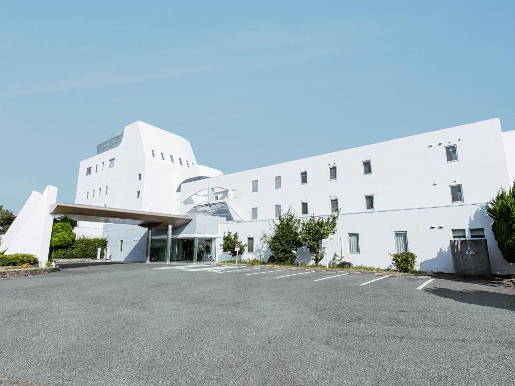 淡路KAMENOI HOTEL Awajishima的白色建筑前的一个空停车位