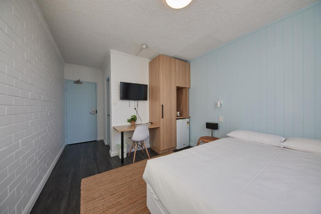 悉尼Little Coogee Hotel的一间卧室配有一张床和一张书桌及电视