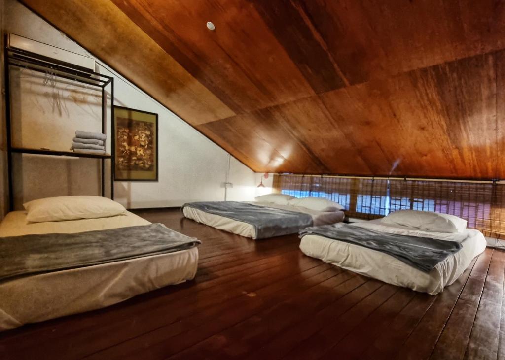 古晋Treehouse Hostel的木天花板的客房内设有三张床