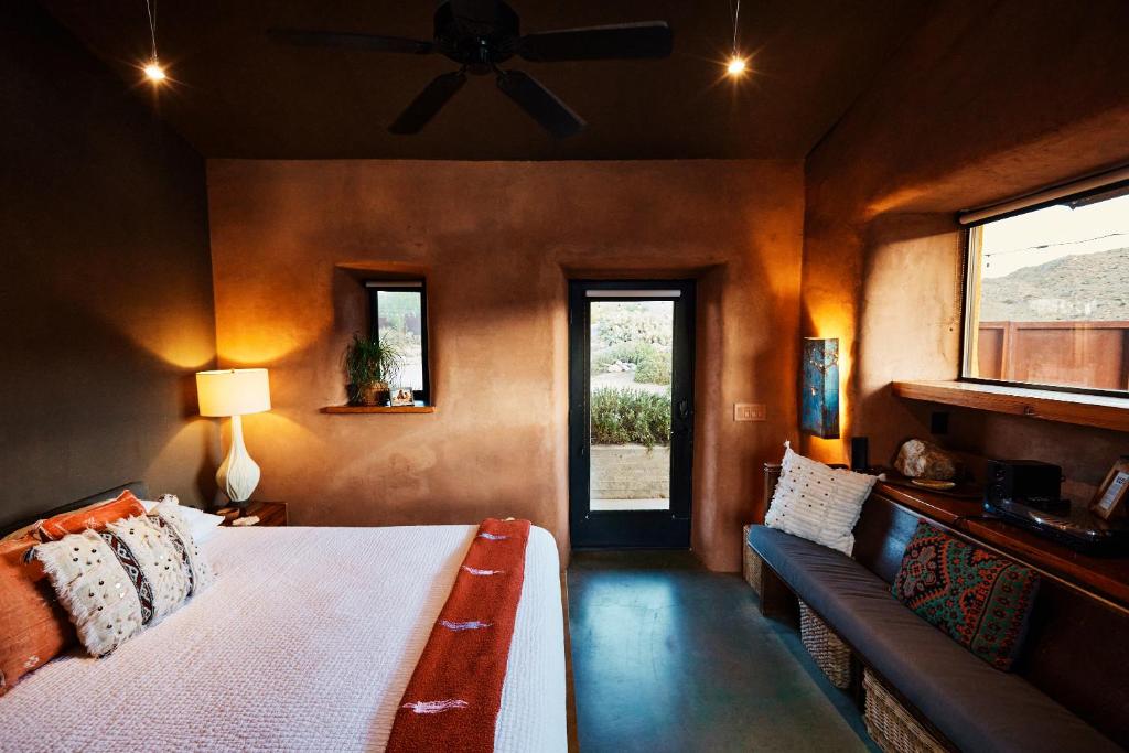 约书亚树Sacred Sands的一间卧室配有一张床、一张沙发和一个窗口