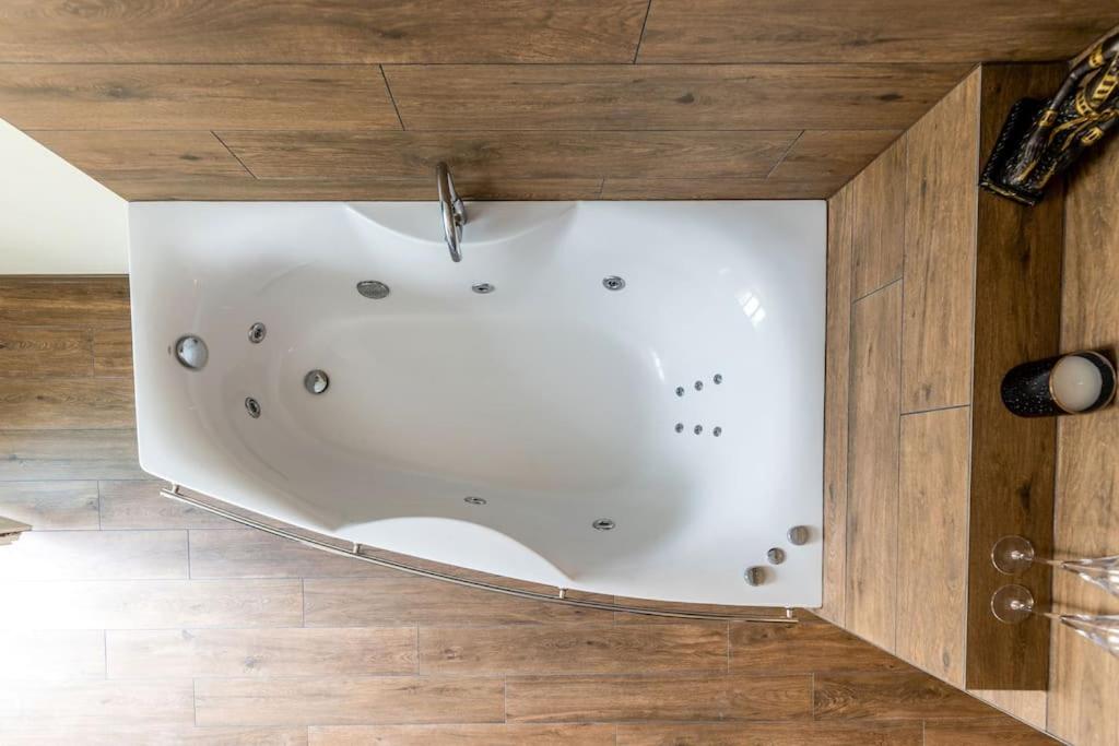 克莱佩达Prabangūs apartamentai su džiakuzi (Jacuzzi)的铺有木地板的客房内设有白色浴缸。