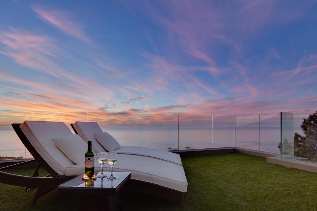 开普敦大西洋黄金酒店的庭院配有白色椅子和一瓶葡萄酒