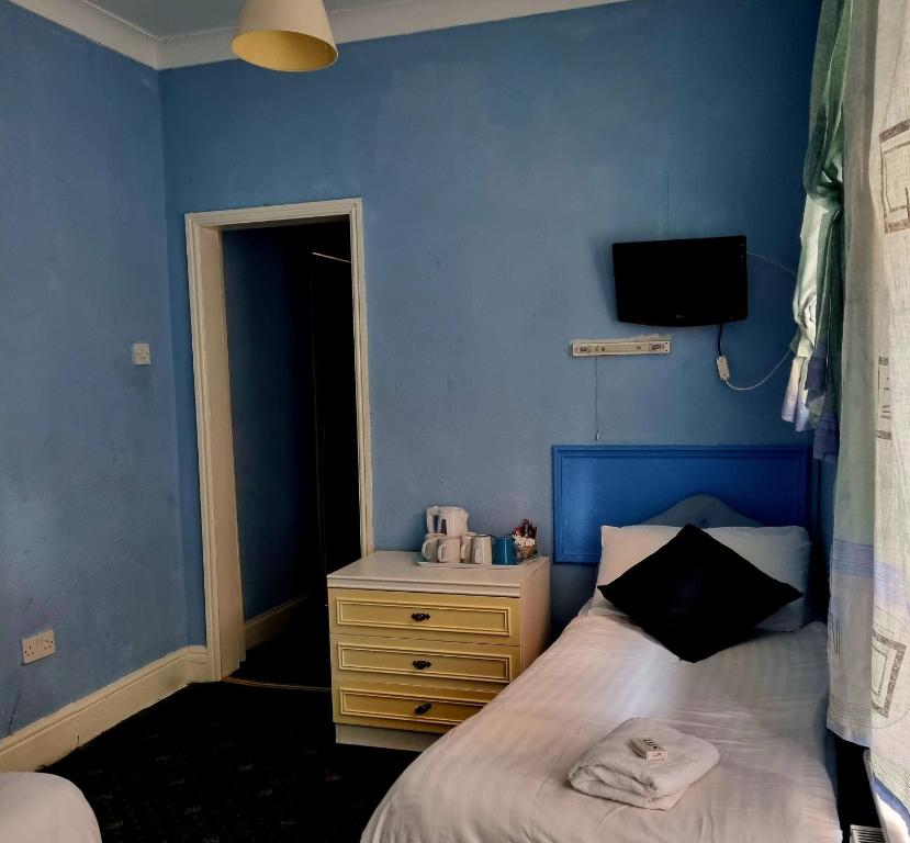 布莱克浦新奥斯特利酒店的一间蓝色卧室,配有床和床头柜