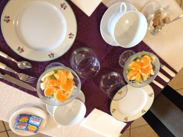 维姆勒Chambre d'hôtes Les Nymphéas的桌子上放有盘子和碗橙子