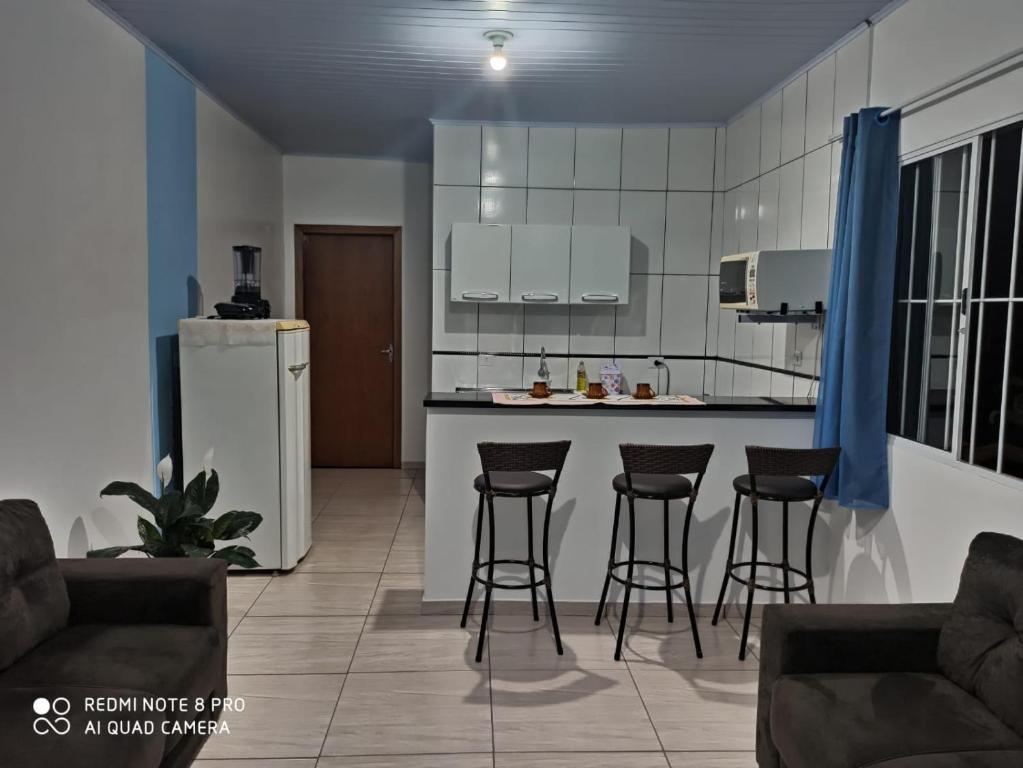 伊瓜苏Casa do aconchego ( terreno compartilhado)的带酒吧凳的厨房和带冰箱的厨房。