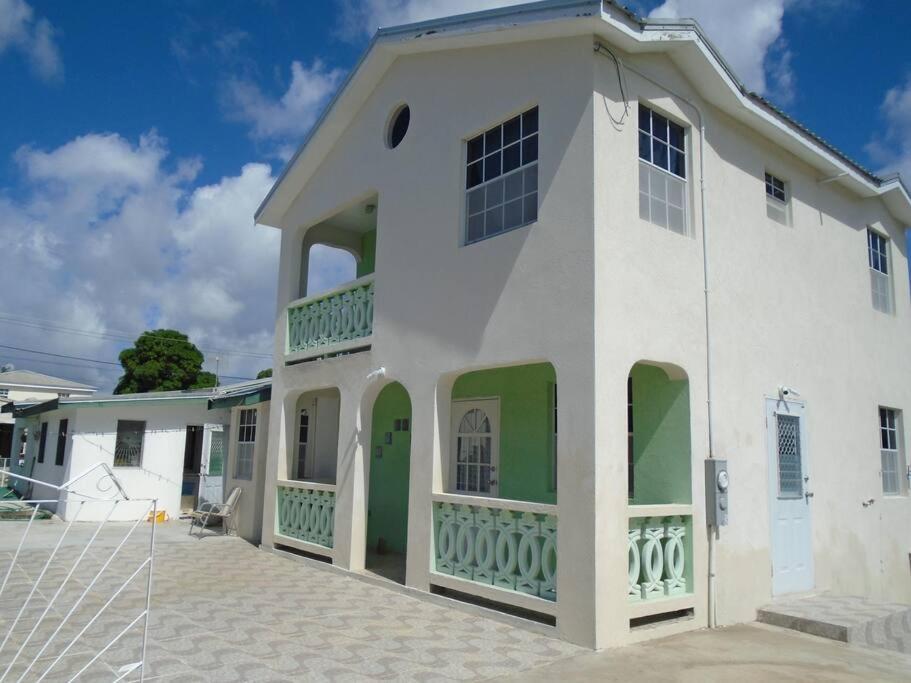 圣詹姆斯Simply Beautiful Two Storey home/apt awaits you的白色的房子,设有绿色的门和窗户