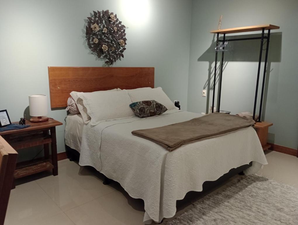 尼泰罗伊Casa da Lu Itacoatiara -Suite Alto Mourão的一间卧室配有一张床和一张带台灯的桌子