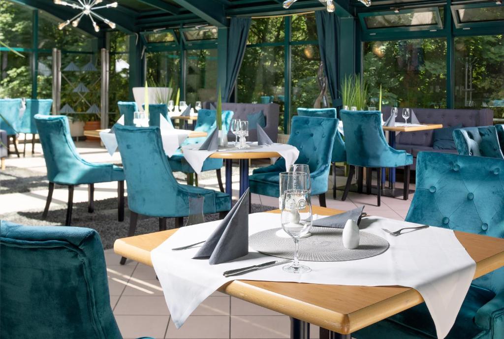 安娜贝格-布赫霍尔茨瓦德施罗森公园酒店的餐厅设有蓝色椅子和桌子,配以酒杯