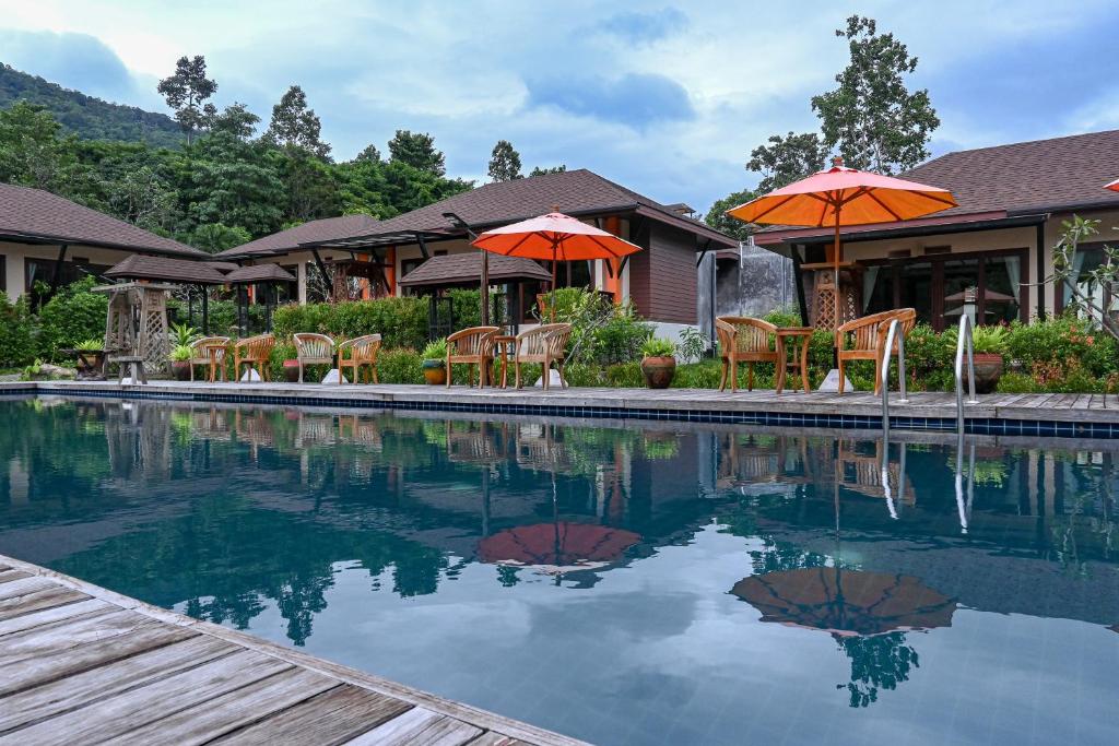 Na MueangCascade Tara的房屋旁的游泳池配有椅子和遮阳伞