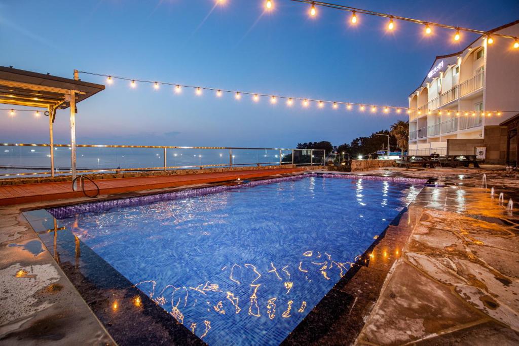 济州市Aewol Oceanstay的一座带灯光的建筑前的游泳池