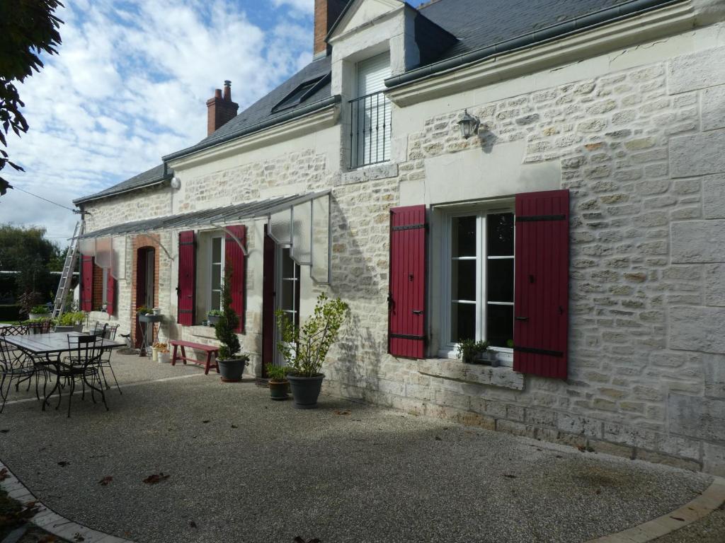Fougères-sur-BièvreChambre d'hotes "Les Paturelles"的白色砖砌的建筑,有红色百叶窗和桌子