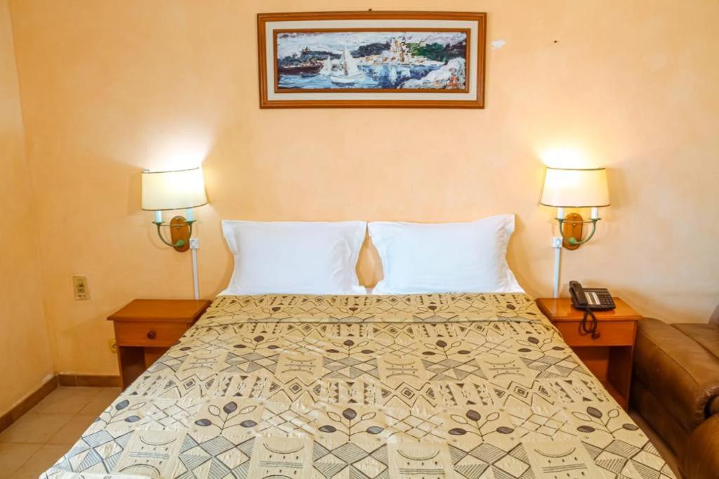 圣路易斯Hôtel La Palmeraie Saint Louis Sénégal的一间卧室配有一张带两盏灯的床和一张沙发。