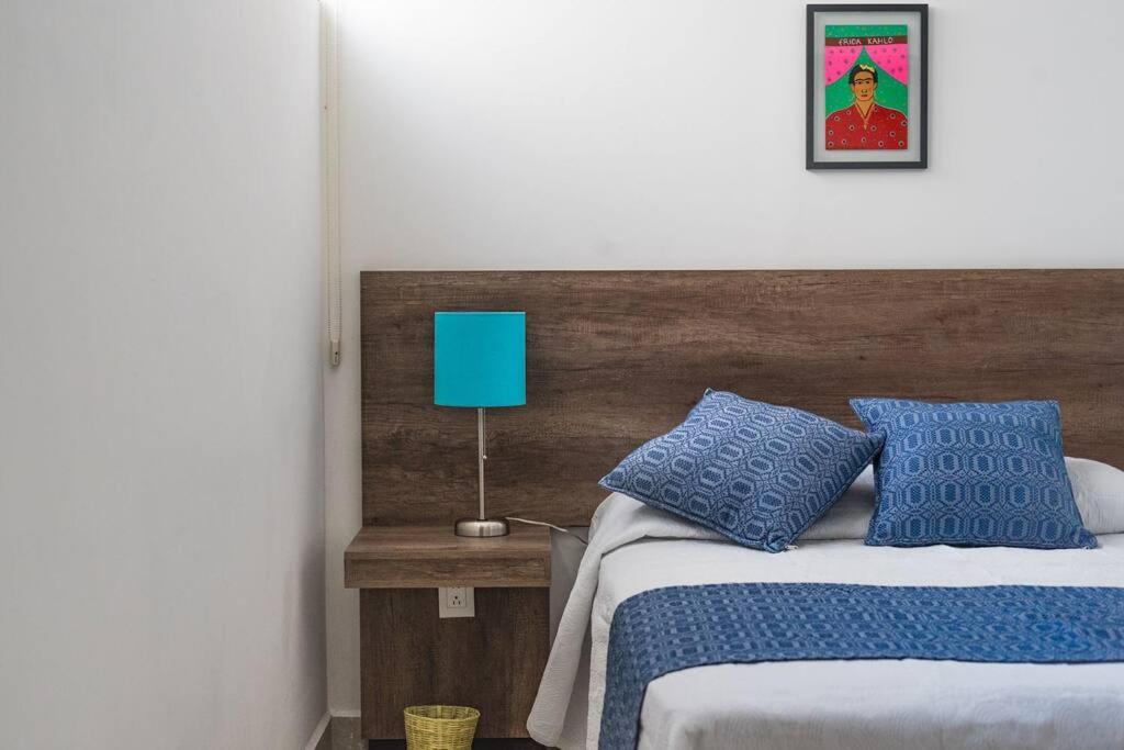 瓦哈卡市JUUB More Oaxaca Impossible (R1)的一间卧室配有一张带蓝色枕头和蓝灯的床。