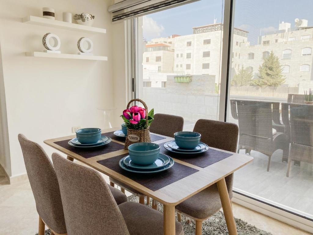 安曼360 Rooftop Apartment in Dabouq的一间带桌椅和窗户的用餐室