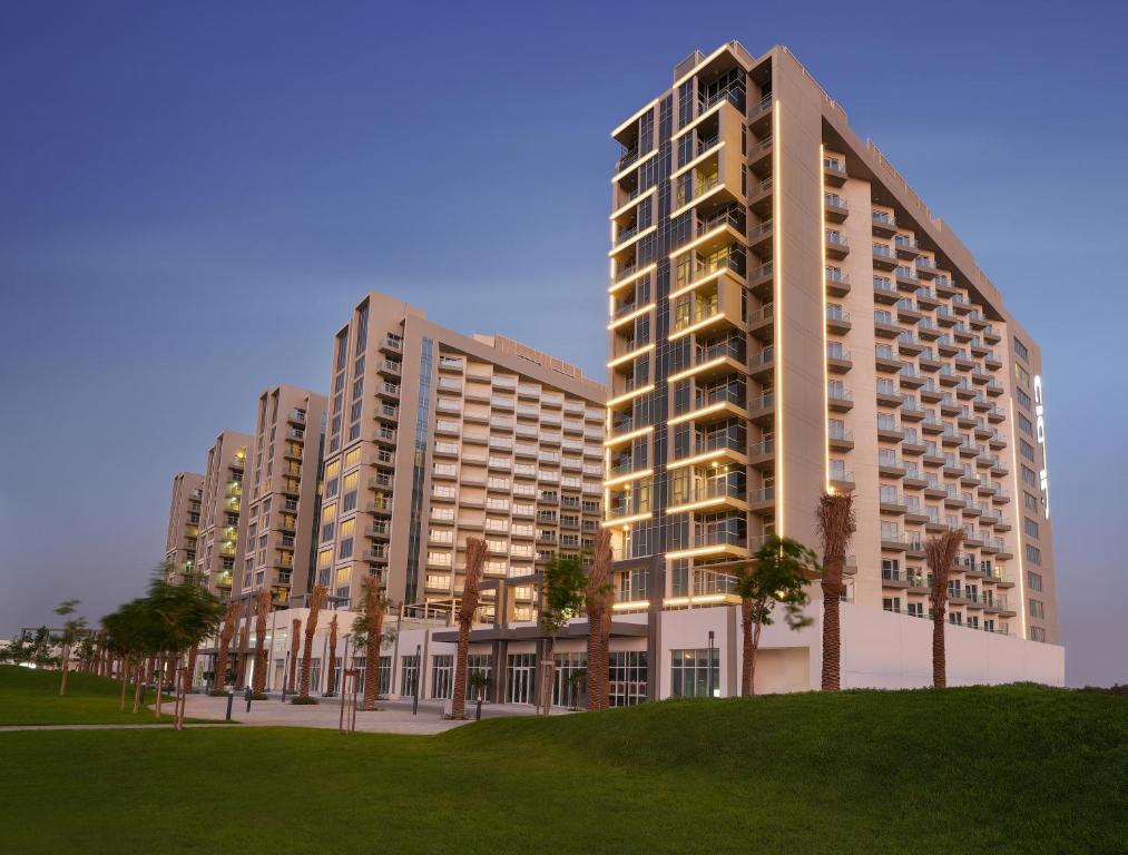 迪拜DAMAC Hills 2 Hotel, an Edge by Rotana Hotel的公园里一群种满棕榈树的高楼