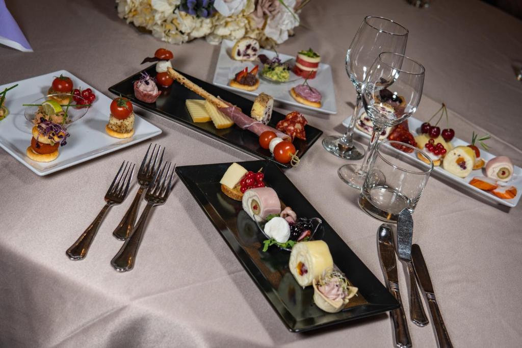 锡比乌精选酒店的餐桌上放有食物和酒杯的盘子
