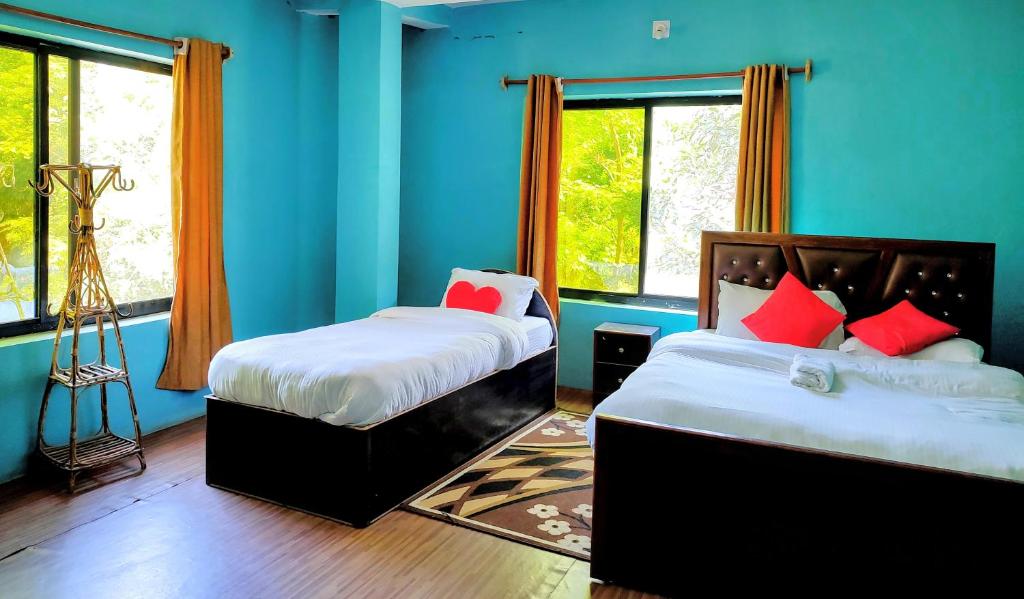 BhurkīāJungle Heaven Hotel and Cottage的配有两张床铺的蓝色墙壁和窗户