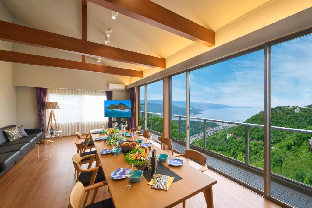 Nakanoスイートヴィラ オーシャンビュー南熱海的一间带桌椅和大窗户的用餐室