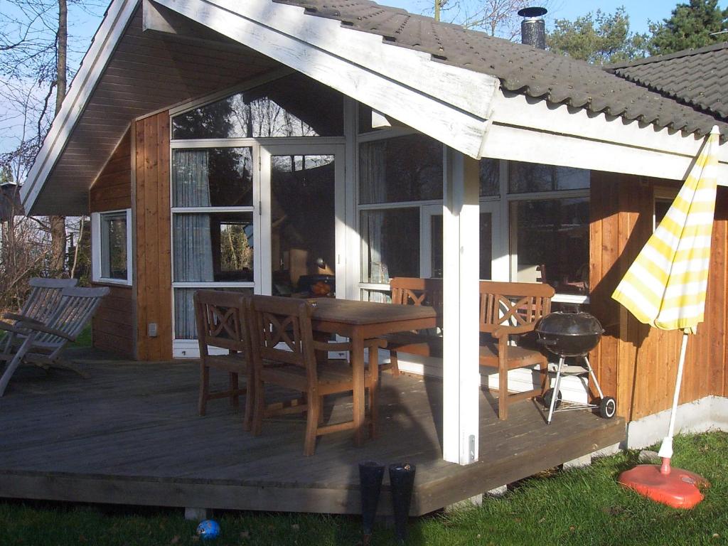 博托比Sommerhus i Marielyst m/Spa og sauna - tæt på by og strand的房屋设有木甲板,配有桌椅