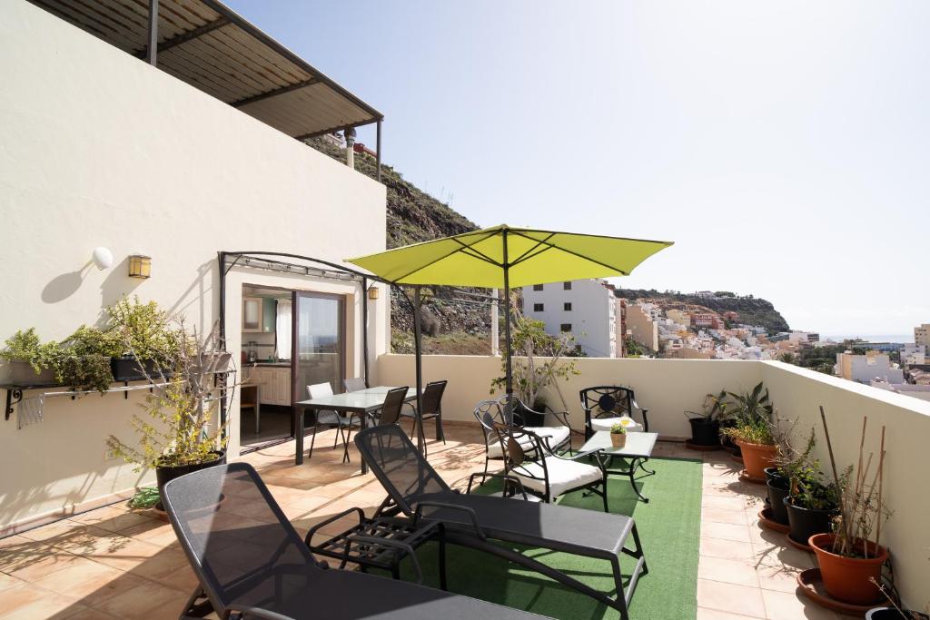 戈梅拉岛圣塞瓦斯蒂安Holiday House Penthouse in La Gomera的一个带桌椅和遮阳伞的庭院