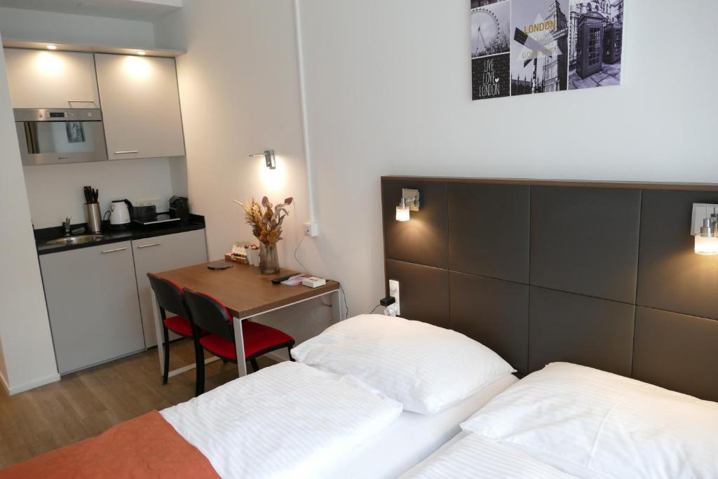 维也纳Comfy Mini Apartments Vienna的带两张床和一张桌子的房间以及一间厨房