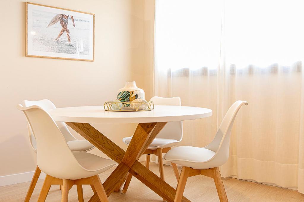 略夫雷加特河畔奥斯皮塔莱特Barcelona Touch Apartments的餐桌周围摆放着白色椅子