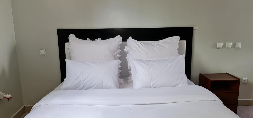 基加利Traveller's StaY的一张带白色床单和枕头的床