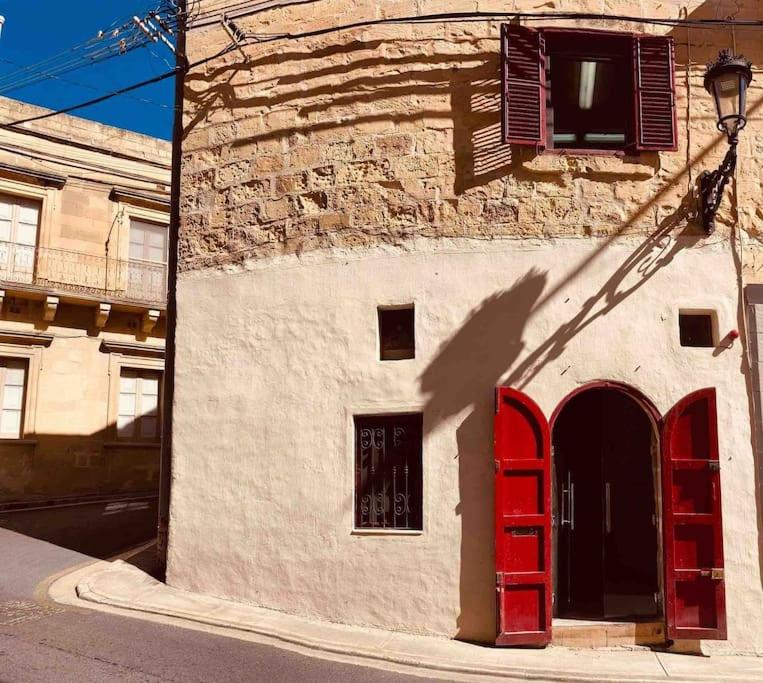 维多利亚300yr old, self catering, tiny house in Victoria Centre, Gozo的建筑的一侧有红色门