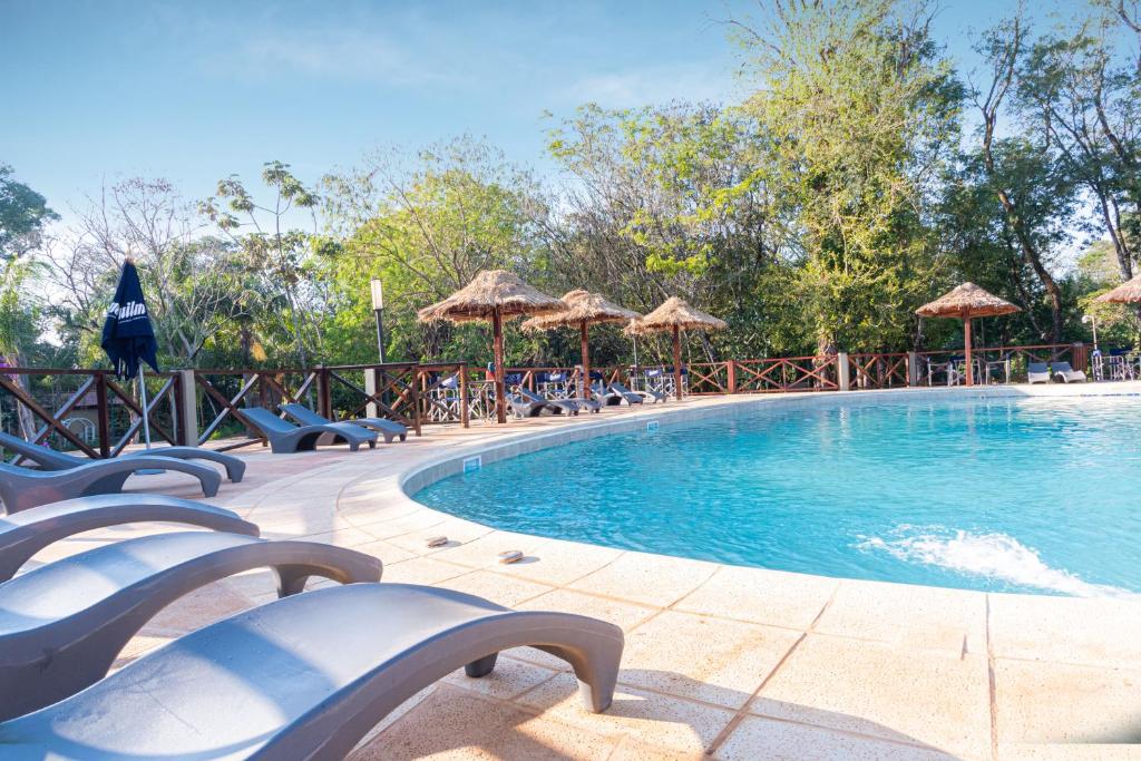 伊瓜苏港卡塔拉塔斯乡村酒店的一个带椅子和遮阳伞的大型游泳池