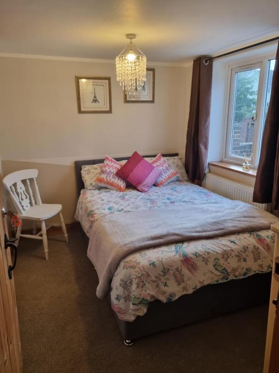 艾尔斯福德Mallard Cottage Guest House的一间卧室配有一张床、一把椅子和一个吊灯。