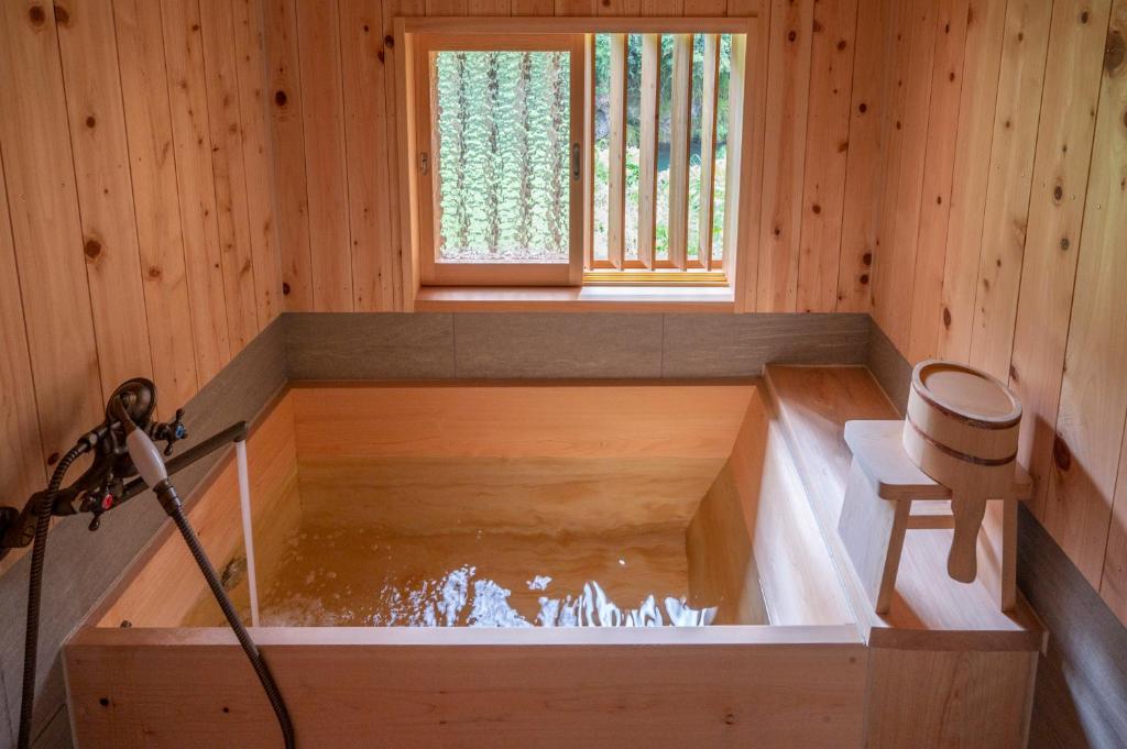 Niyodogawa古民家一棟貸し宿　山のめぐみ舎的木制房间内的浴缸,里面装有水